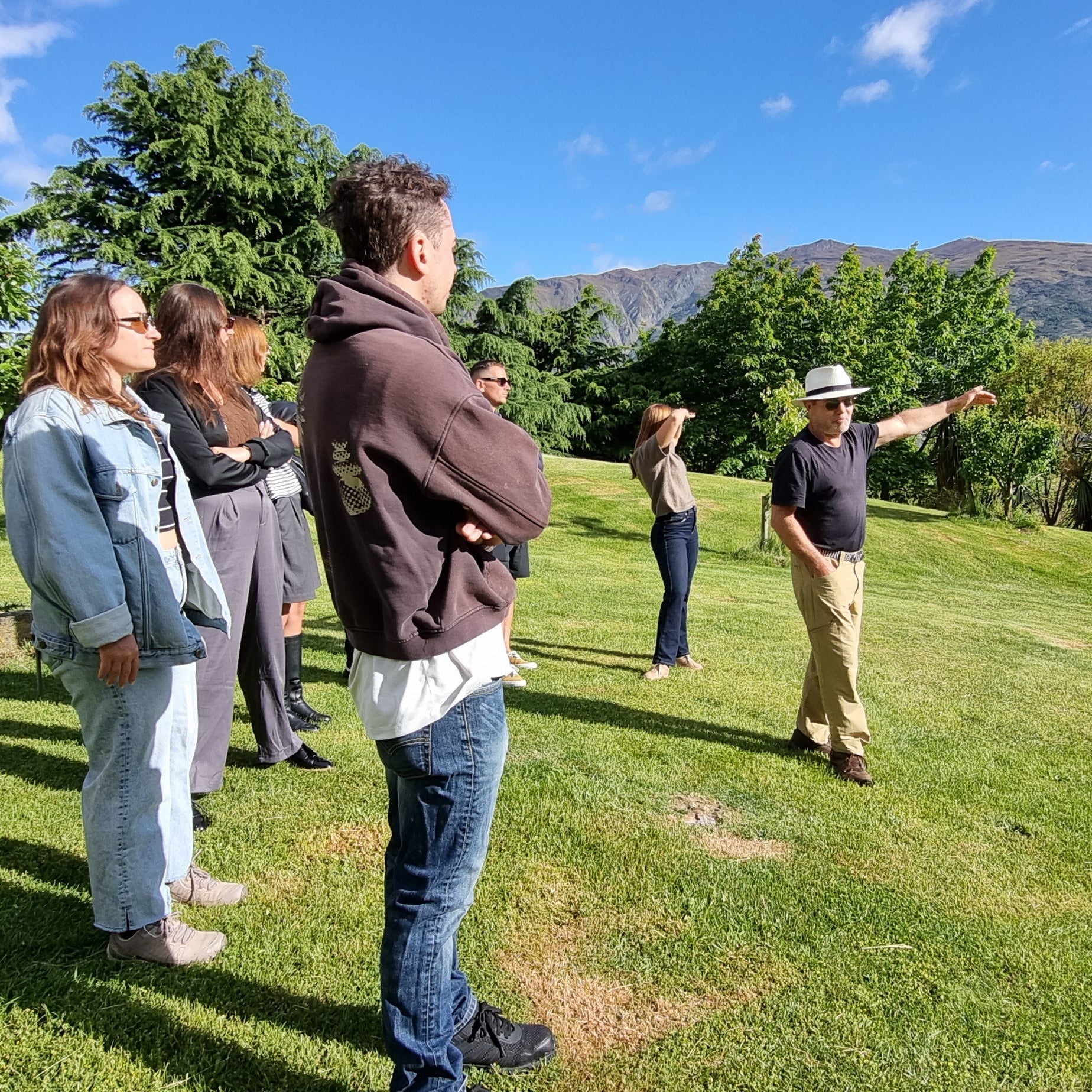 Group of people standing on a grassy area with mountains in the background