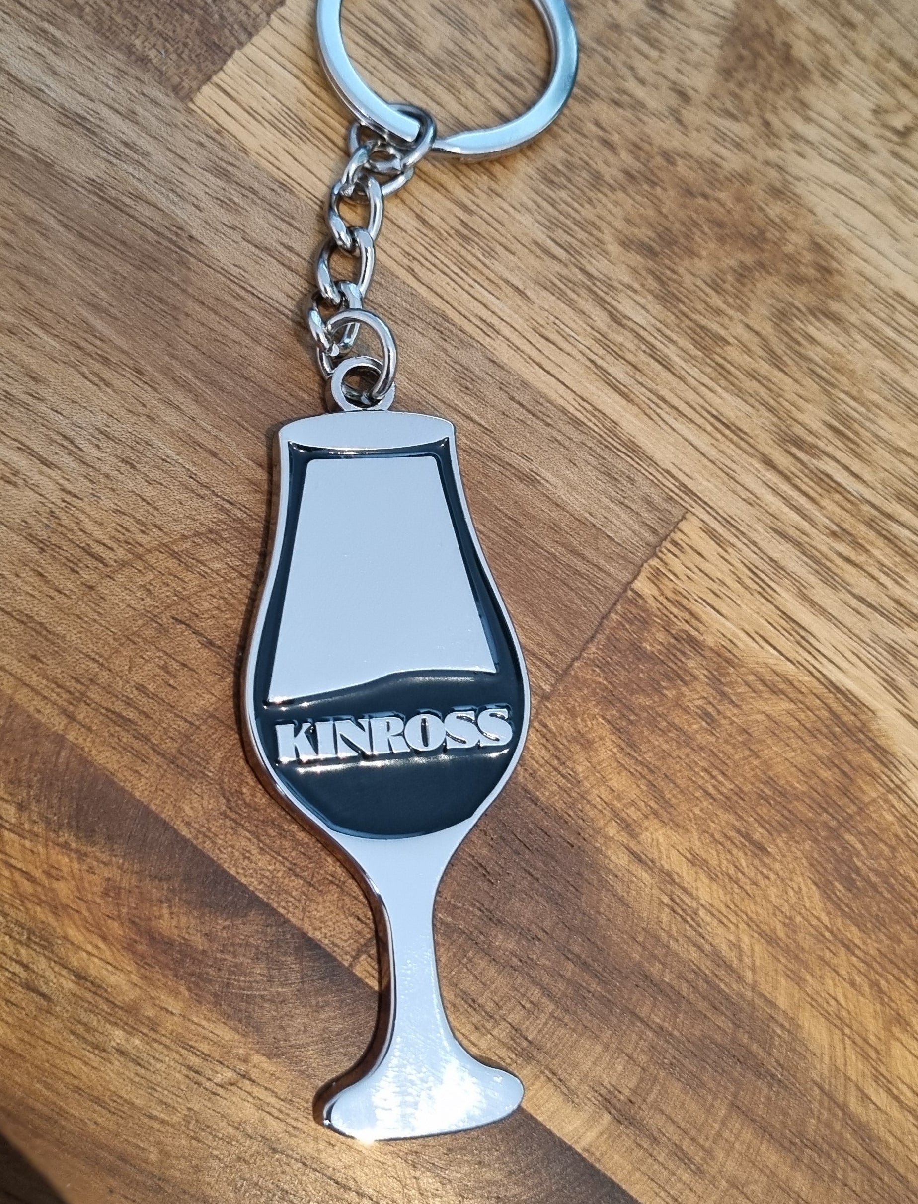 Metal keychain shaped like a bottle opener on a wooden surface